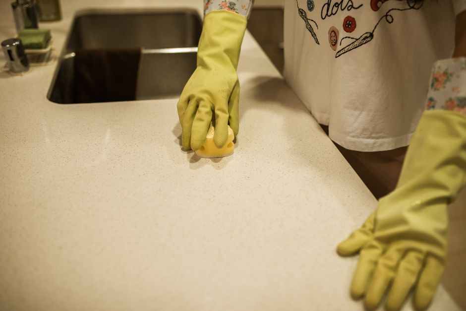 Person wiping a kitchen counter with a sponge